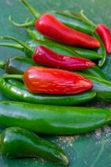 Capsicum annuum Jalapeno chilli hot peppers, group of green and red fruits on wooden colorful table background