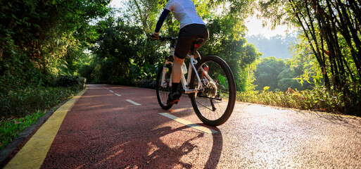 Woman cycling on bike path at sunrise park