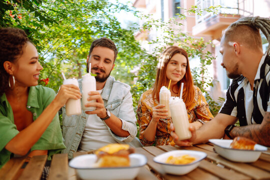 Summer  milkshake. Young friends celebrating summer and drinking milkshakes in a cafe. People, lifestyle, lunch, party, relax concept.