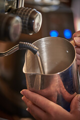 Close up barista using espresso machine milk frother