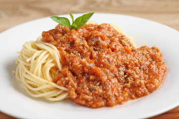 Close up a fork with spaghetti and red sauce in white dish on cutting board