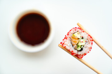 sushi sticks keep roll with a cup of soy sauce on white background