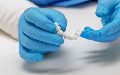 dentist holds ceramic dental crowns in his hands, zirconium bridge, close-up - obrazy, fototapety, plakaty