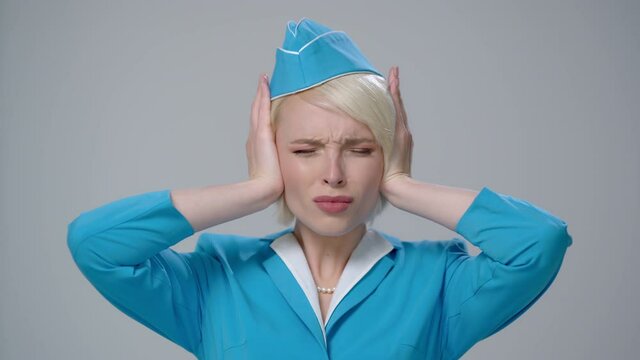 Stewardess in a stressful situation. Fright, hysterics, phobia. Gray background.