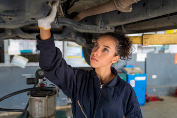 Service repair maintenance concept. African American woman work for auto mechanic in garage checking car engine. A car mechanic is changing the oil in a car repair workshop.