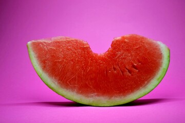 Fresh bitten watermelon slice isolated on a pink background