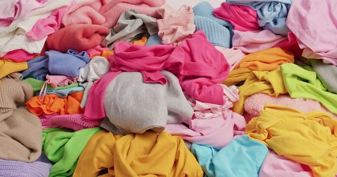 Messy dirty laundry textile. Multicolored clothes prepared for donation. Big pile of clothing. Discounts and sale. Cluttering and recycling concept. Untidy cluttered wardrobe. Nothing to wear