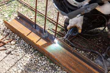 A welder welds metal at a construction site.