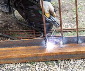 A welder welds metal at a construction site.