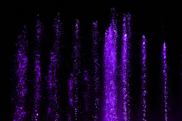 Splashing fountain in purple color at night