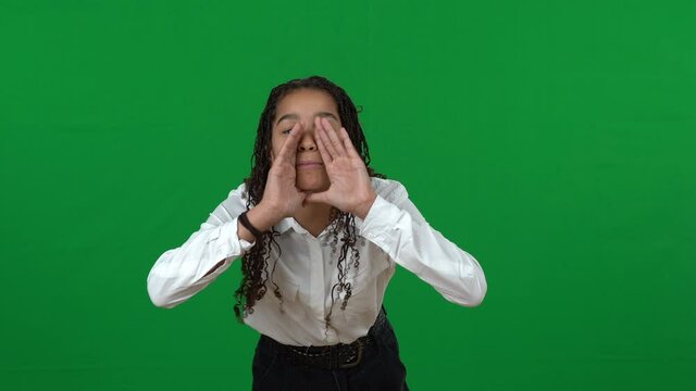 Lost African American teenage girl shouting holding hands at mouth on green screen. Portrait of disorientated teenager at chromakey background calling for help