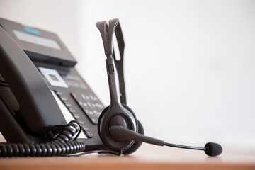 Communication support, call center and customer service help desk. VOIP headset on telephone keyboard.