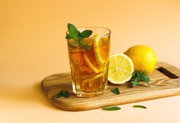 Iced tea with lemon slices and mint on wooden table. Close up summer vitamin antioxidant beverage. Copy space for text. Cold longdrink or lemonade.