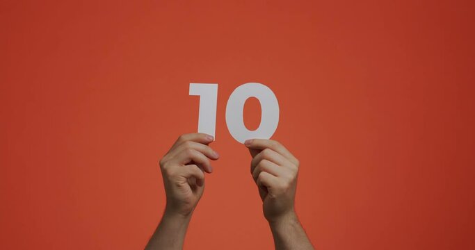 Number ten in hands. Man showing digits, 10 made of carved paper for voting or mathematics learning