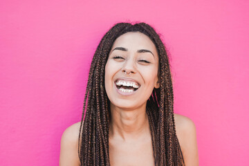 Beautiful mixed race young woman with braids smiling - Pink background
