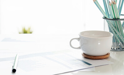 Closeup white cup and paperwork with copy space.