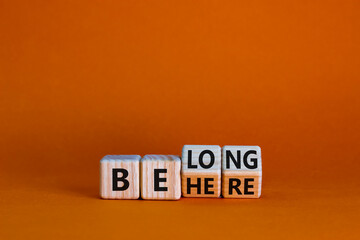 Be here belong symbol. Turned cubes and changed words 'be here' to 'belong'. Beautiful orange background. Business, belonging and be here belong concept. Copy space.