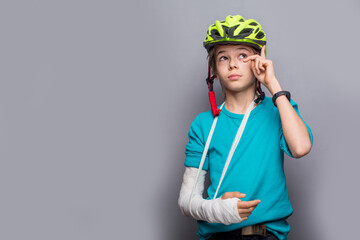 Handsome boy with broken arm over grey background