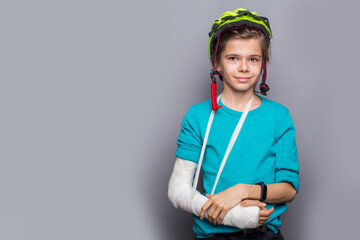 Handsome boy with broken arm over grey background