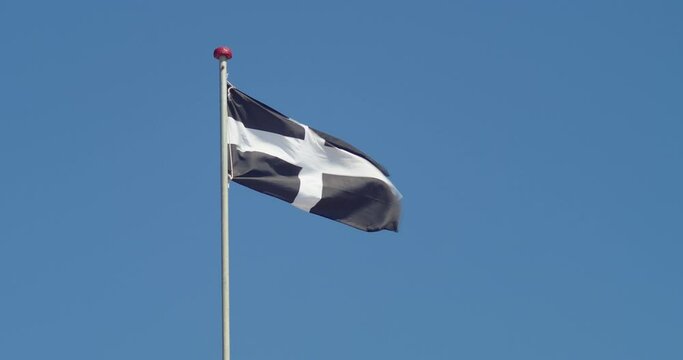 Cornwall Flag - Saint Piran's Flag On Pole Waving In The Wind With Blue Sky In The Background. - wide shot