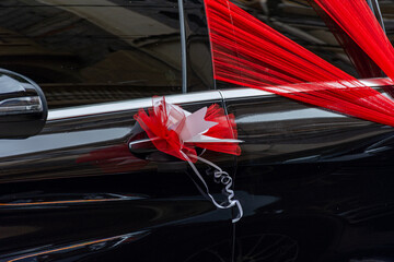 Black wedding car, red organza fabric, ribbon bow.