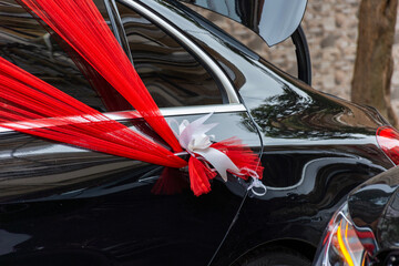 Black wedding car, red organza fabric, ribbon bow.
