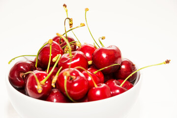 Obraz na płótnie Canvas Red cherries inside a white cup on a white background
