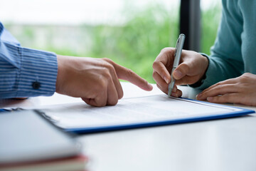 Businesswoman signing a document or application form in a folder, Businessmen hand's pointing where...