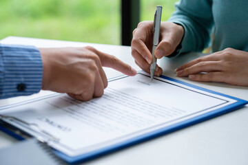 Businesswoman signing a document or application form in a folder, Businessmen hand's pointing where to sign a contract, legal papers or application form.
