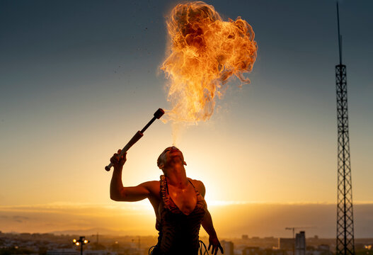 Fire-eater artist performing spit fire at sunset