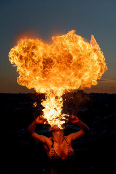 Fire-eater artist performing spit fire at sunset