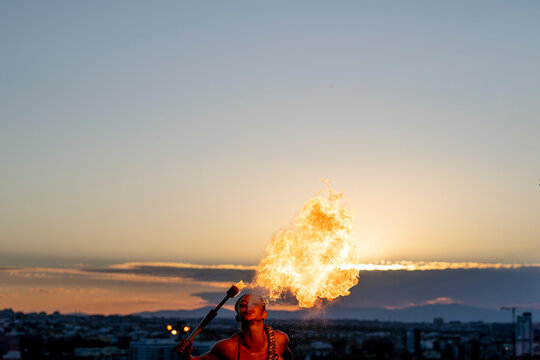 Fire-eater artist performing spit fire at sunset