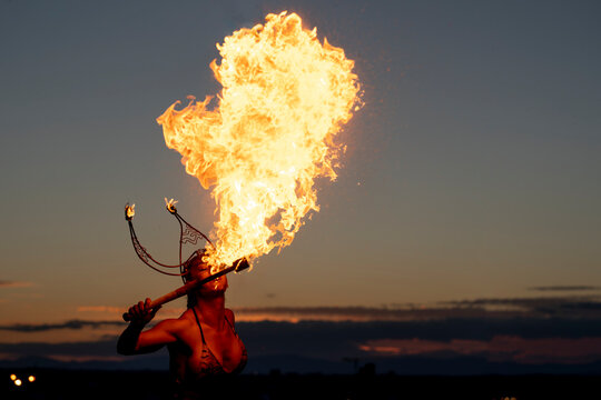 Fire-eater artist performing spit fire at sunset