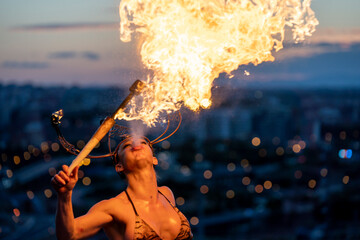 Fire-eater artist performing spit fire at sunset
