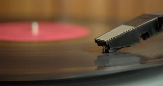 Close up of a vinyl record spinning in an old electric turntable. The pickup needle runs along the groove.