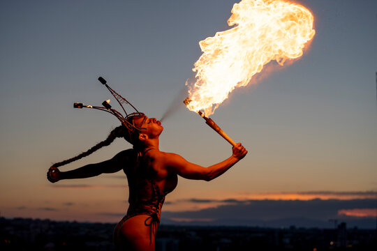 Fire-eater artist performing spit fire at sunset