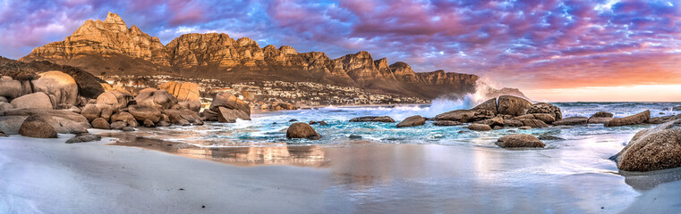 Breathtaking sunset panorama of the iconic Table Mountain and the Twelve Apostles range, Cape Town South Africa. A unique and scenic wide-angle perspective taken from Maidens cove beach