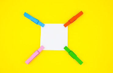 Blank white To Do List Sticker with colorful wooden clothespins. Close up of reminder note paper on the yellow background. Copy space. Minimalism, original and creative photo.
