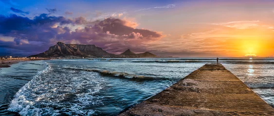 Photo sur Plexiglas Montagne de la Table Picturesque and colourful sunset scene of Table Mountain and The Atlantic Ocean. A jetty reaches out to the cool blue sea to inspire a sense of adventure. A stunning tourist destination - Cape Town