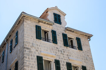 Fototapeta na wymiar Medieval buildings. Old town of Kotor Montenegro on the blue sky background. An old building with open windows.