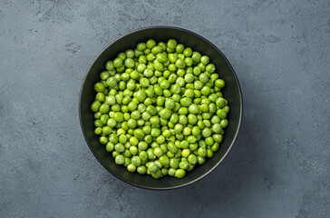 Fresh peeled green peas on a dark gray background.