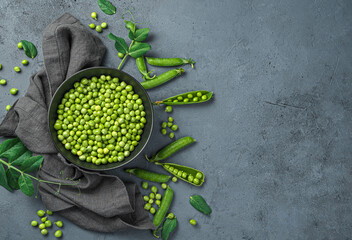 Peeled peas in a bowl and pods on a gray background. Top view, copy space.