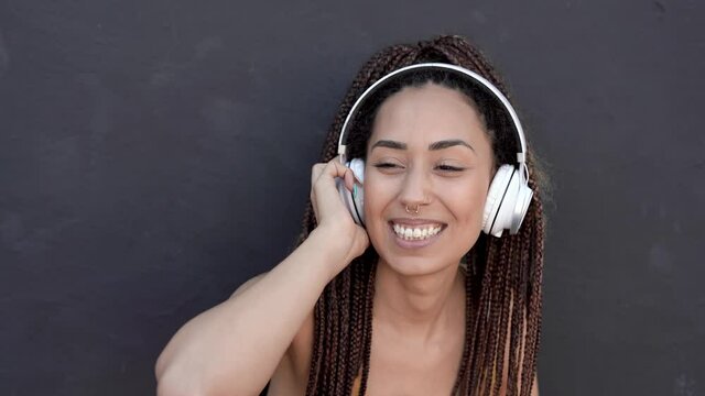 Young mixed race woman dancing to music playlist wearing wireless headphones 