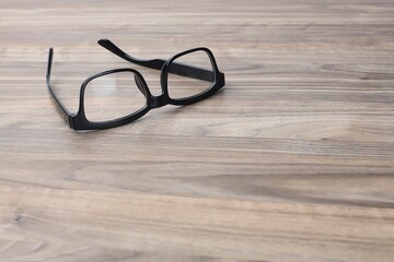 Black frame eyeglasses isolated on the wooden table
