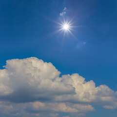 Naklejka na ściany i meble sparkle sun above dense cumulus clouds, natural sky background