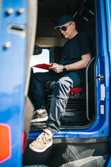 Experienced truck driver sitting in his truck and waiting for a new driving route.