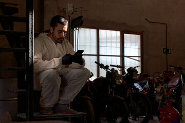 Male mechanic relaxing during break in workshop with motorbikes