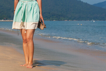 woman holding sandals on a beach in Penang Malaysia