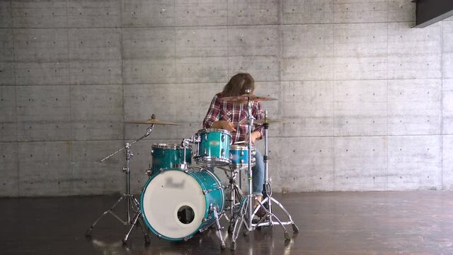 Long or Wide Shot of Attractive Beard Stylish Guy entering the frame and siting down to play the drums. 
