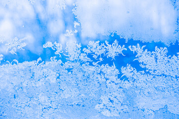 Frosty patterns on glass. Frosty texture on a blue background. Frosted window.